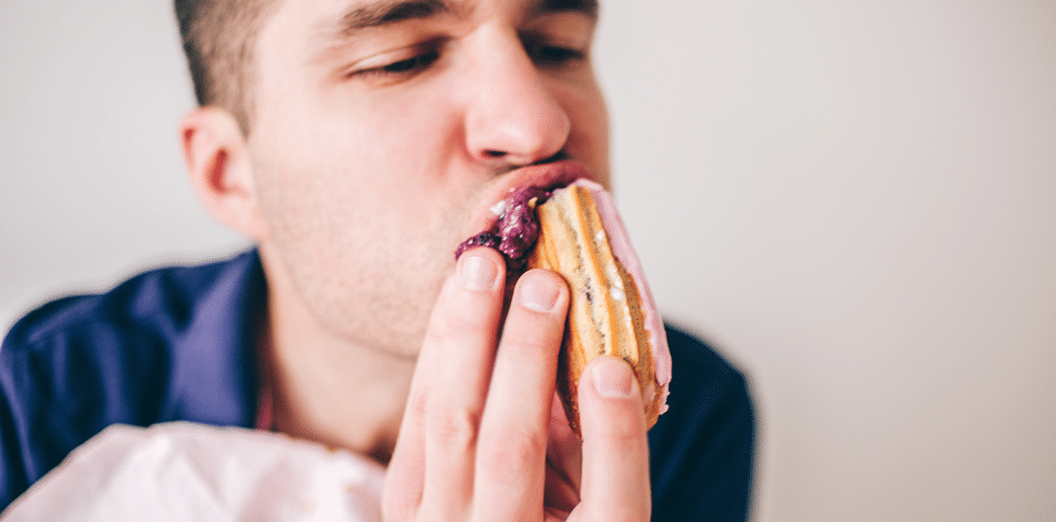 Person eating a sugary pastry that can contribute to tooth decay and enamel damage in Tarneit